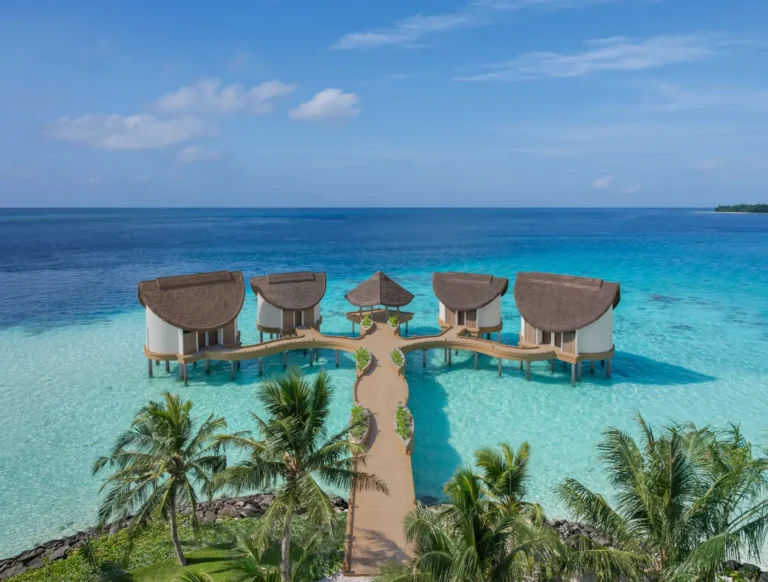 Hotel Openings 128 Aerial view of the overwater JW Marriott Kaafu Atoll Island Resort, surrounded by crystal-clear turquoise waters in the Maldives.