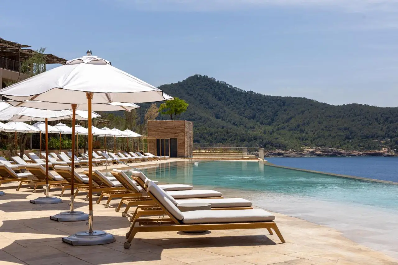 Poolside view at Six Senses Ibiza with lounge chairs and scenic sea backdrop.