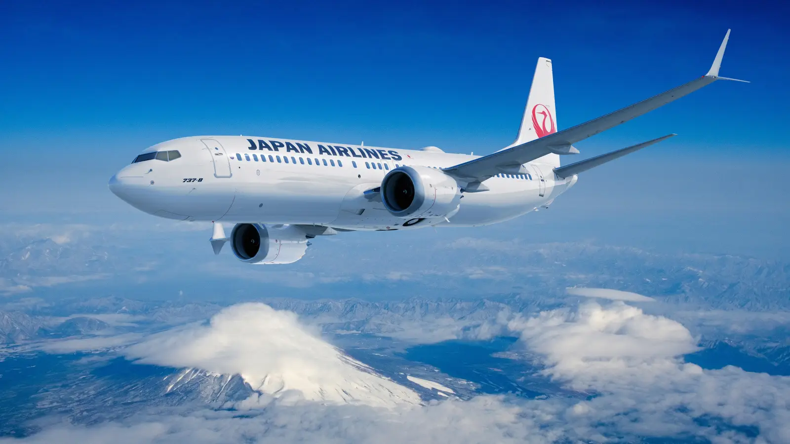 Japan Airlines Boeing 737-8 flying above clouds with Mount Fuji in the background