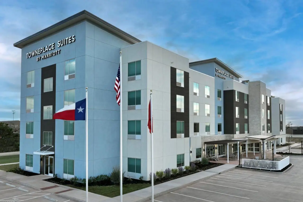 Exterior view of TownePlace Suites by Marriott Abilene Southwest, featuring a modern four-story building with American, Texas, and Canadian flags.