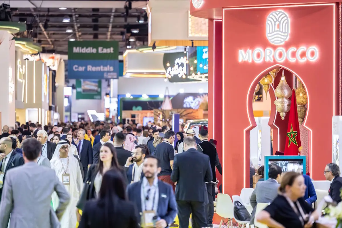 Bustling exhibition hall at Arabian Travel Market with attendees and a Morocco pavilion.