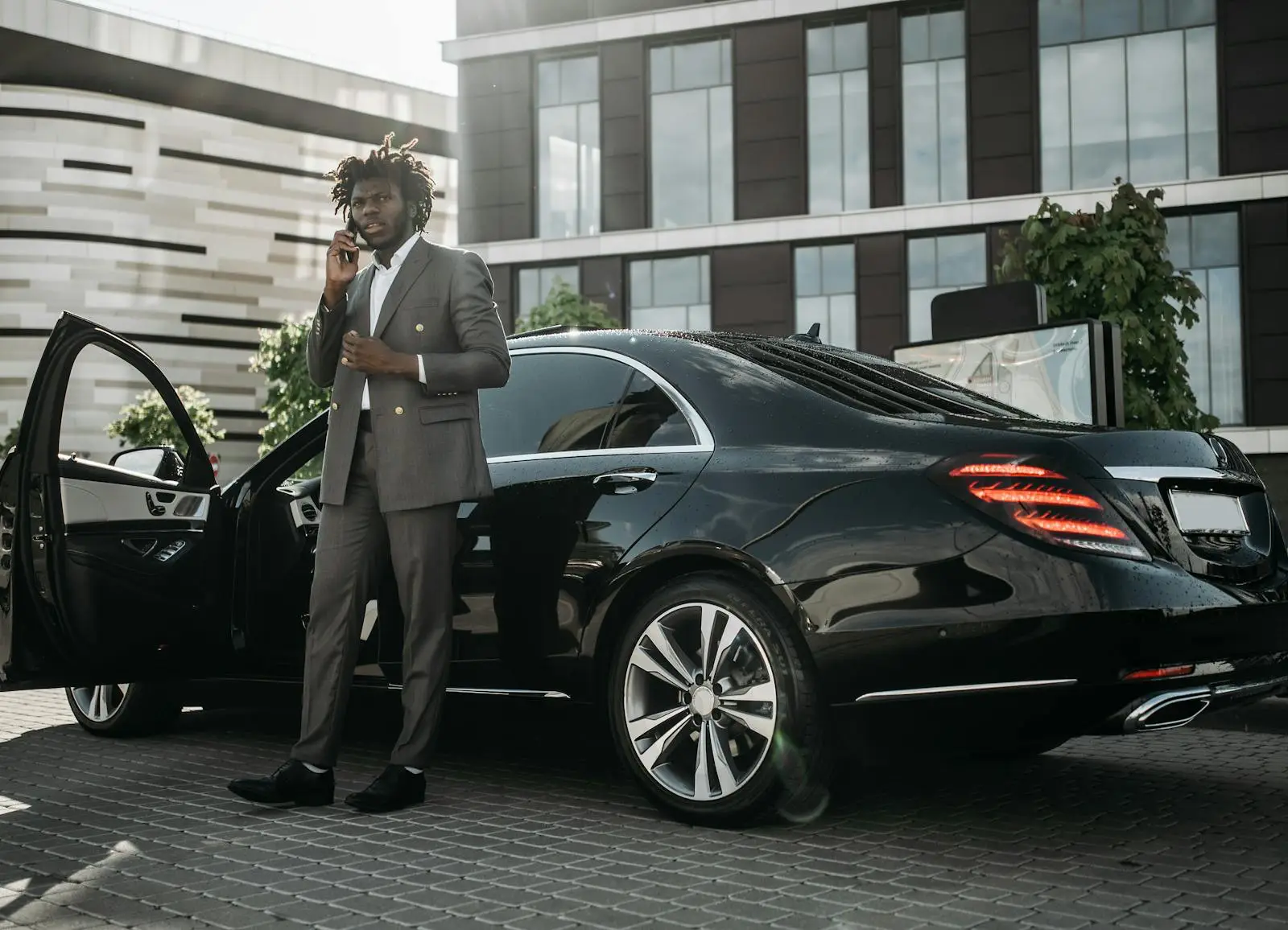 U.s. Black Travelers Boost 2025 Travel Spend 1 Stylish Black man in a suit standing by a luxury car while on a phone call