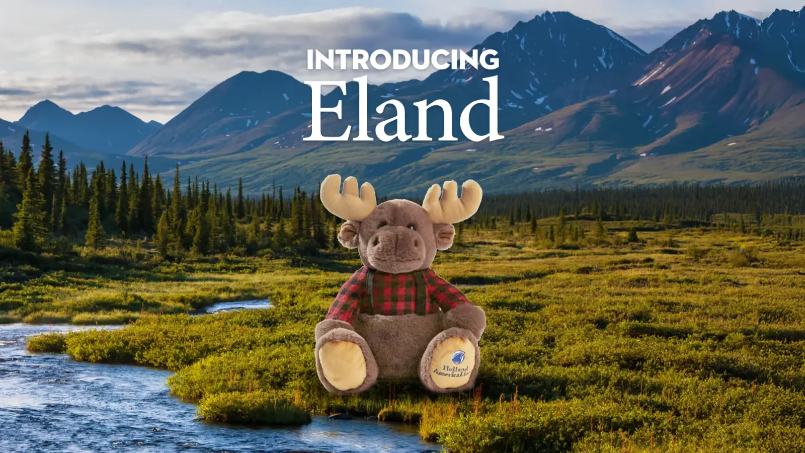 Eland the Moose plush toy wearing a red plaid shirt, set against an Alaskan wilderness backdrop with mountains, forests, and a flowing river.