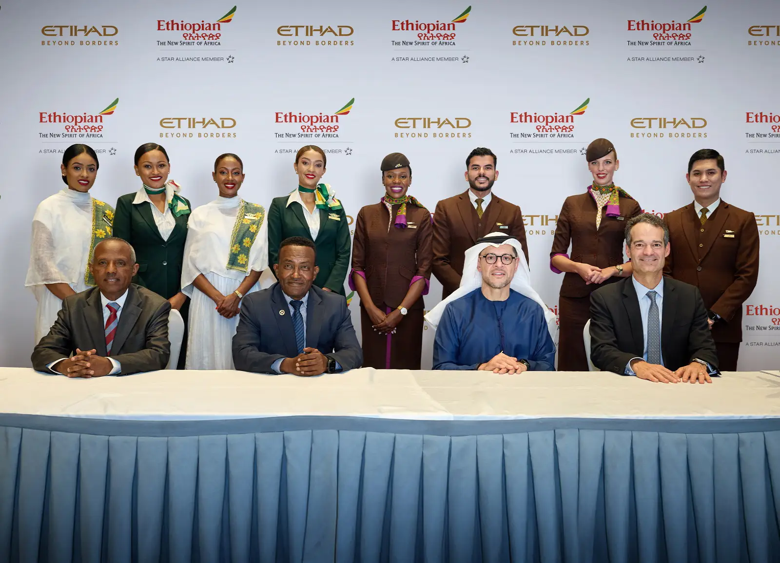 Etihad And Ethiopian Airlines Expand Networks With Joint Venture 11 Senior executives from Etihad Airways and Ethiopian Airlines sit at a table during the official signing ceremony of their joint venture agreement, with flight attendants from both airlines standing behind them.