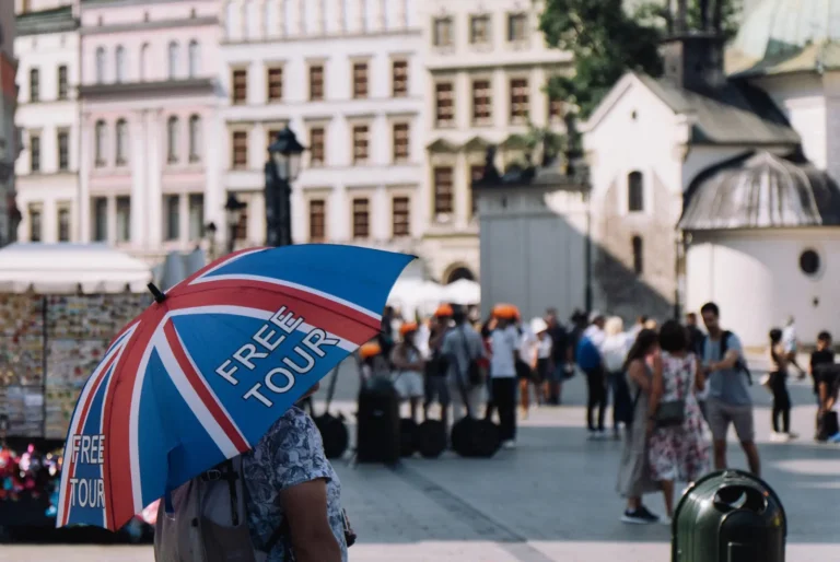 Tour guide holding a Union Jack umbrella labeled “Free Tour” in a busy European city square