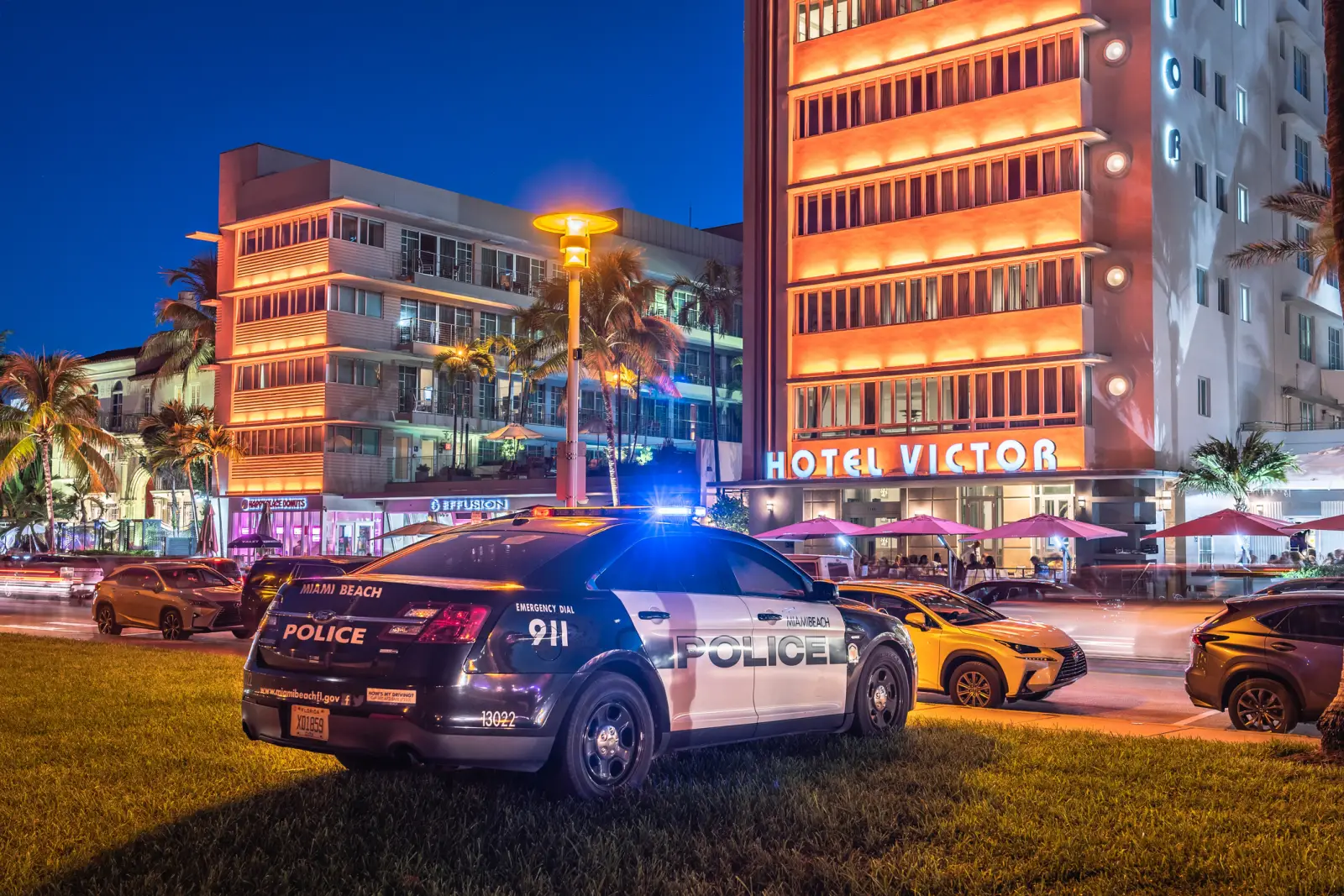 Rental Car Accidents In Florida: What Are Your Rights And Who’s Responsible? 5 A Miami Beach police car with flashing lights parked near Hotel Victor at night, with illuminated buildings, palm trees, and traffic on Ocean Drive, Florida.
