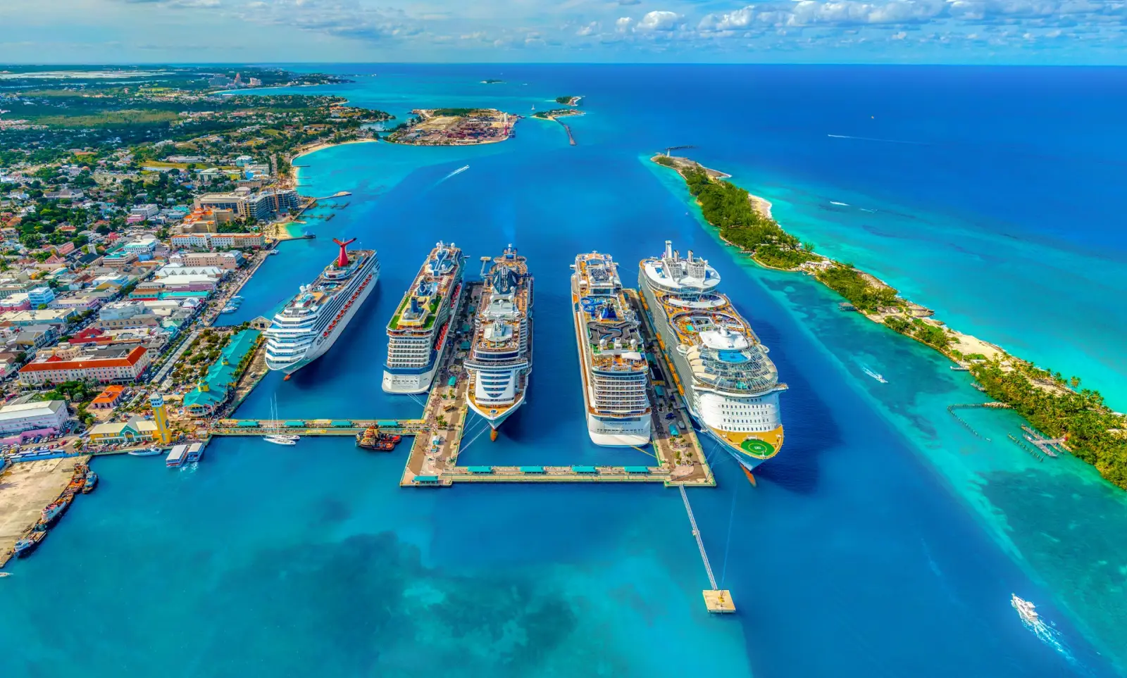 Aerial view of Nassau Cruise Port in The Bahamas, featuring several docked cruise ships and turquoise waters.