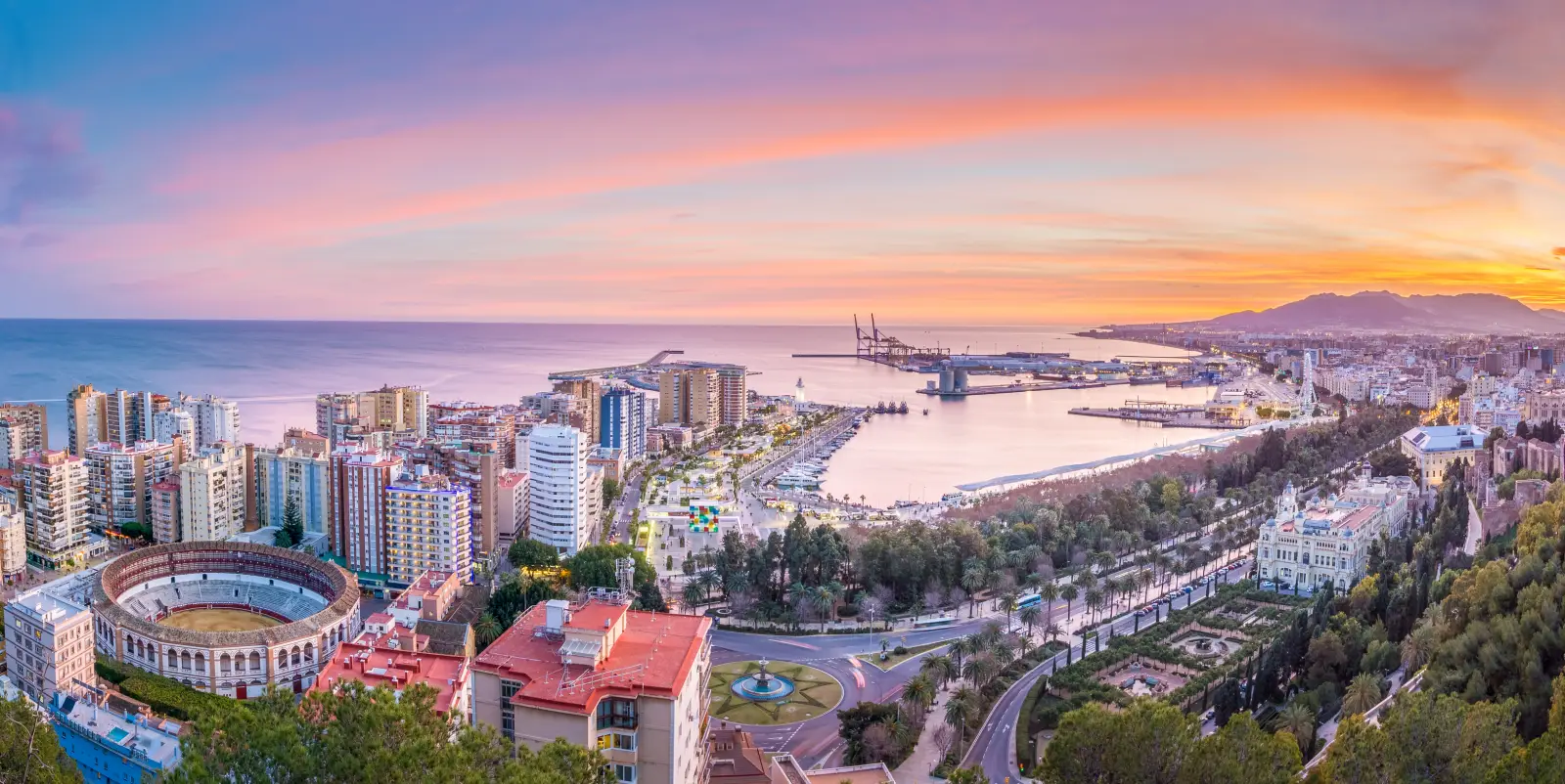 Panoramic view of Malaga city and harbor at sunset, with the bullring, port, and coastal skyline