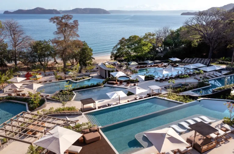 Luxury Travel 26 Waldorf Astoria Costa Rica beachfront resort with tiered pools, sun loungers, and lush tropical landscaping overlooking the Pacific Ocean.