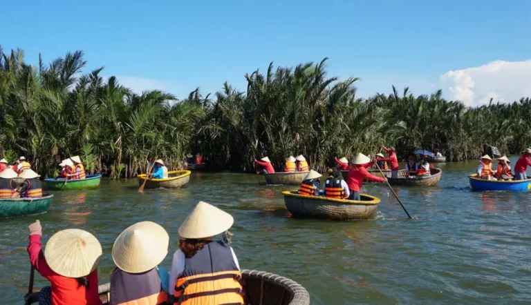 Tourists wearing life jackets and Vietnamese conical hats enjoy a traditional basket boat ride through coconut palm waterways in Hoi An, Vietnam.