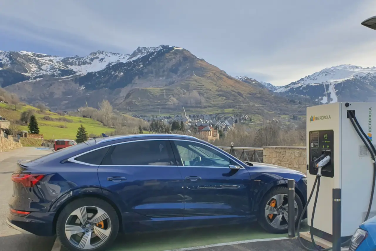 Spain’s Ev Charging Map Goes Live With 25,000+ Real-Time Stations 10 A dark blue electric SUV charging at an Iberdrola EV station in the Spanish Pyrenees, with snow-capped mountains and green valleys in the background.