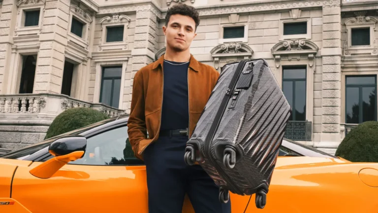 Luxury Travel 18 Lando Norris holding a TUMI 19 Degree Lite carry-on beside an orange sports car