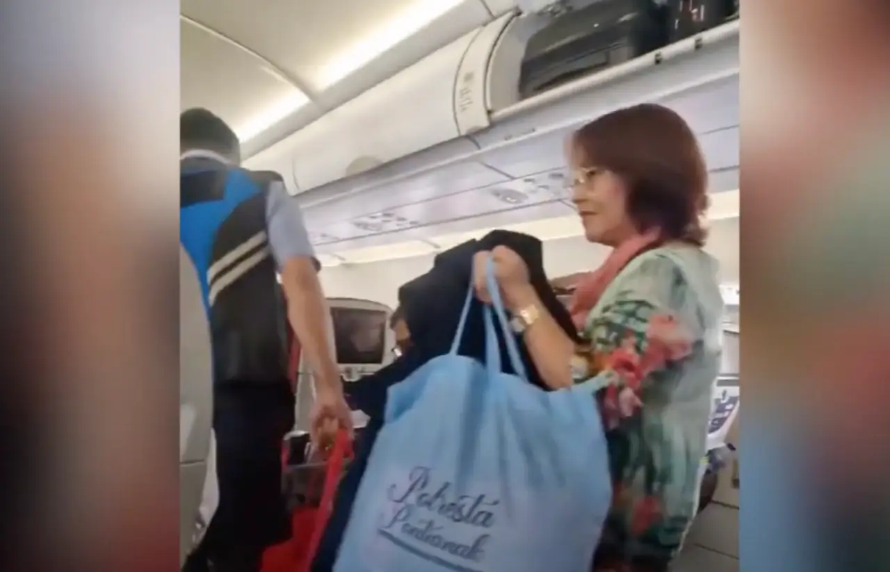 Elderly woman calmly exiting an airplane cabin with her luggage after being removed from a flight in Indonesia