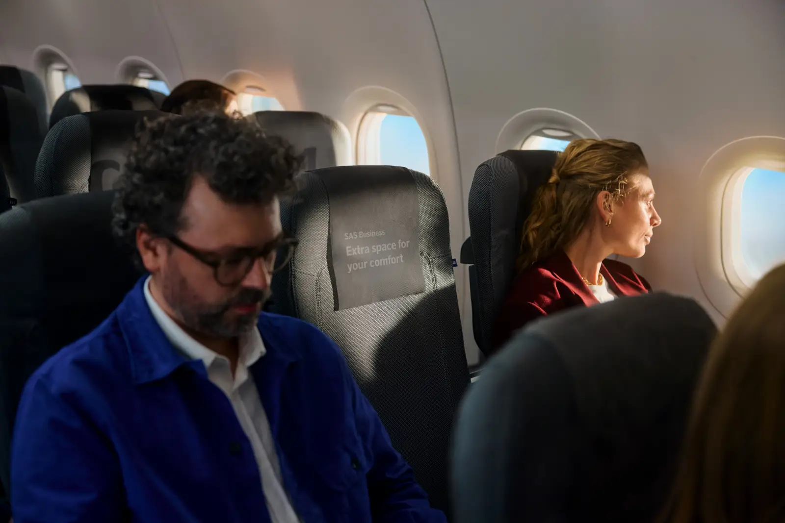 Passengers seated in SAS Business Class with an empty middle seat for added comfort.