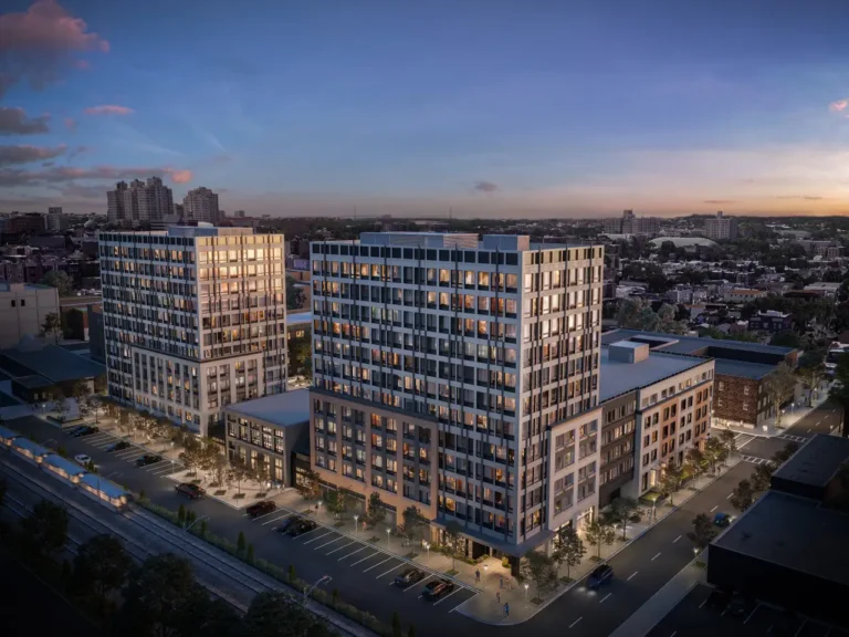 Aerial view of West Side Square development in Jersey City at dusk, featuring two modern high-rise residential buildings surrounded by city streets and parkingAerial view of West Side Square development in Jersey City at dusk, featuring two modern high-rise residential buildings surrounded by city streets and parking