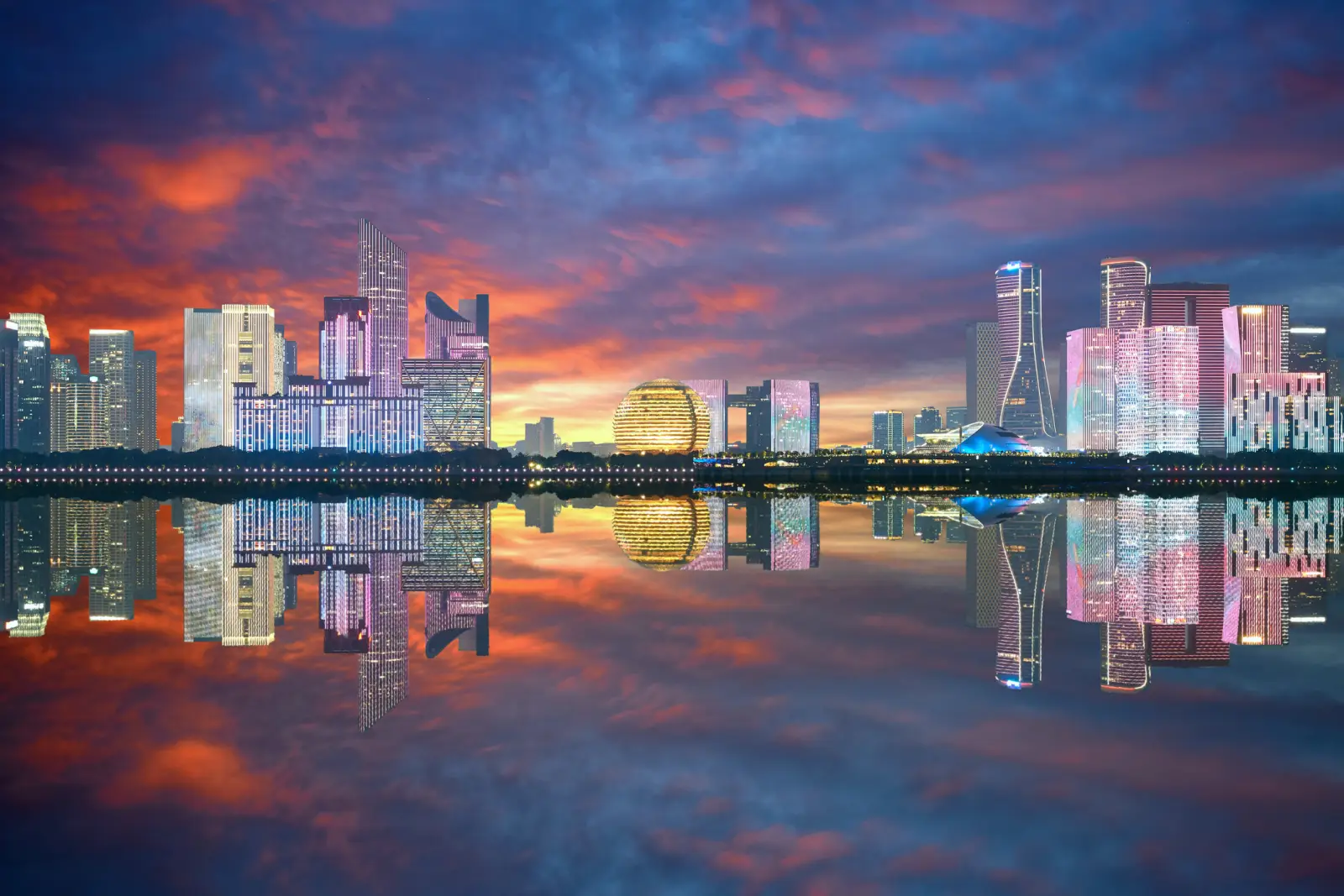 Hangzhou skyline at sunset with modern skyscrapers and colorful reflections on water.