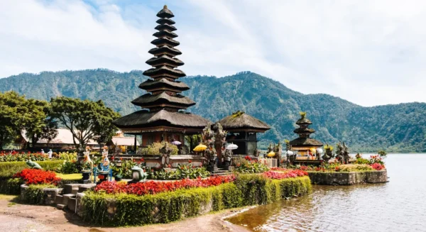 Balinese temple surrounded by colorful flowers with a mountain backdrop