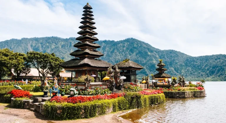 Balinese temple surrounded by colorful flowers with a mountain backdrop