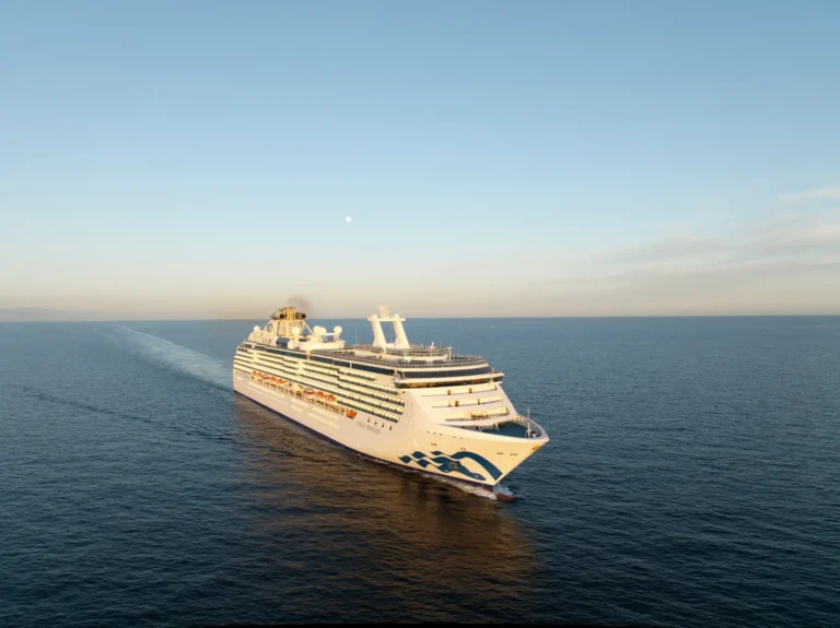 Coral Princess cruise ship sailing across calm ocean waters during sunset.