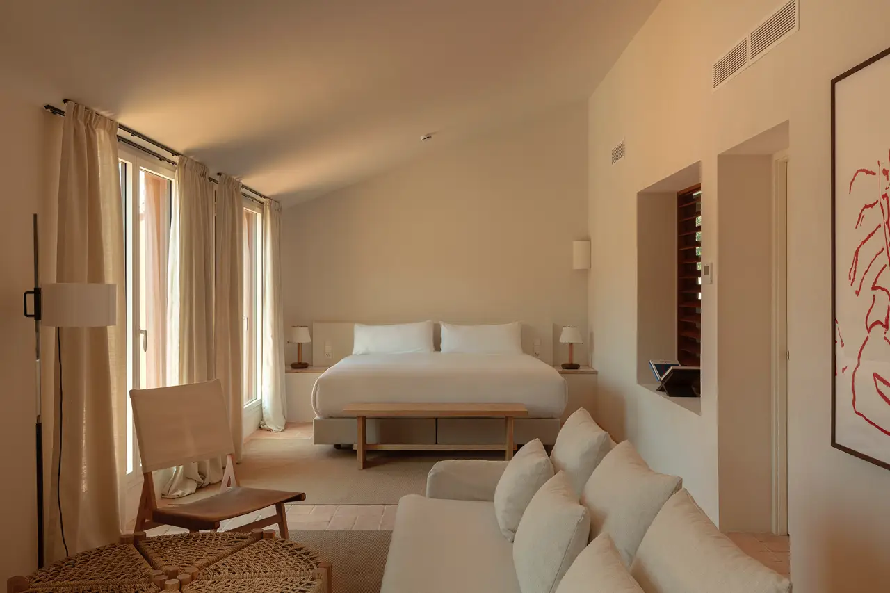 Elegant suite at Finca Victoria with a king-size bed, natural light, neutral tones, and cozy lounge area.