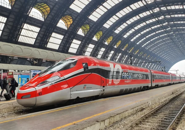 Frecciarossa high-speed Trenitalia train at a station platform under an arched glass roof.