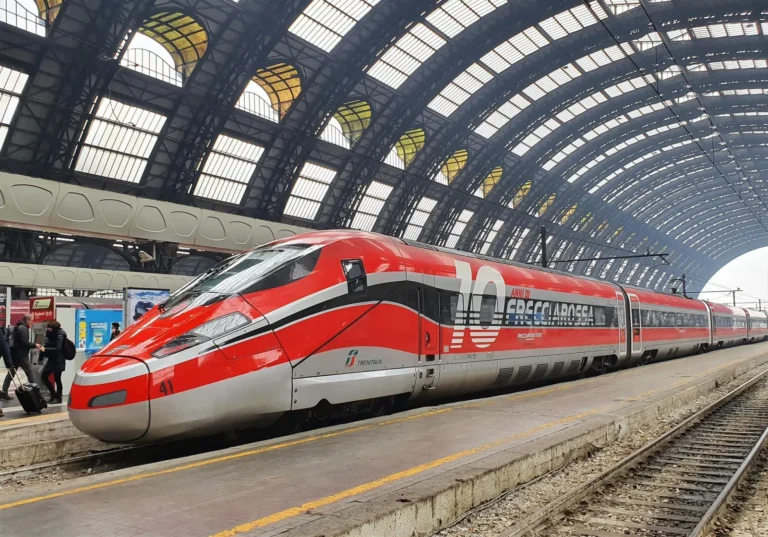 Frecciarossa high-speed Trenitalia train at a station platform under an arched glass roof.
