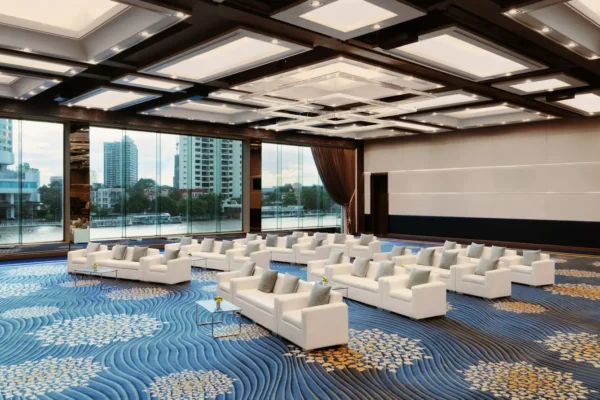 Modern riverside meeting room at Royal Orchid Sheraton Bangkok with white sofas and floor-to-ceiling windows overlooking the Chao Phraya River
