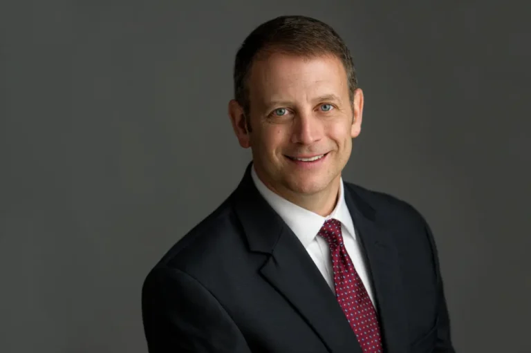 professional portrait of Ed Simon in dark jacket with white shirt and a red tie