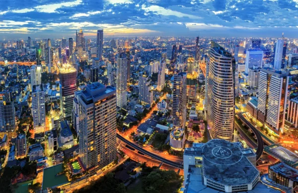 Home 8 Aerial view of Bangkok at night with illuminated skyscrapers and city streets.