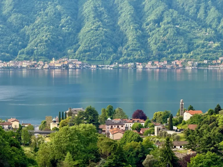 Luxury Travel 22 A scenic view of Lake Como with colorful villages along the shore and lush green mountains rising in the background.