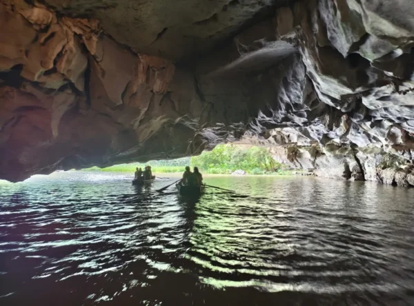 Tourists paddle through a limestone cave on a sampan boat in Tam Coc, Ninh Binh, Vietnam.