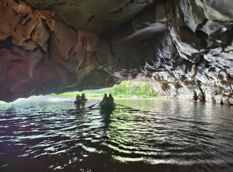 Tourists paddle through a limestone cave on a sampan boat in Tam Coc, Ninh Binh, Vietnam.