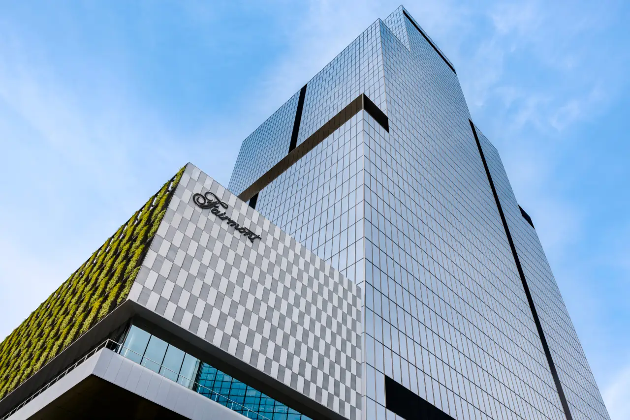 Fairmont Tokyo Opens, Marking Brand’s First Hotel In Japan 20 Exterior view of the new Fairmont Tokyo hotel, a modern glass skyscraper in the Shibaura district with the Fairmont logo on the facade against a blue sky.