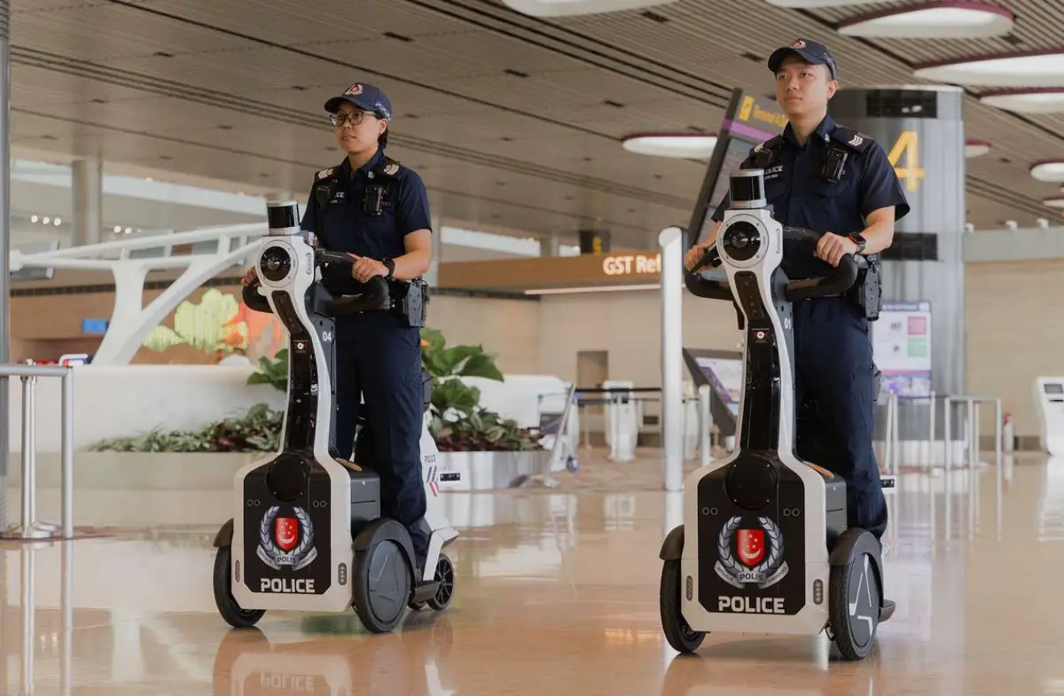 Two Singapore police officers riding GIBSON patrol robots inside Changi Airport Terminal 4.