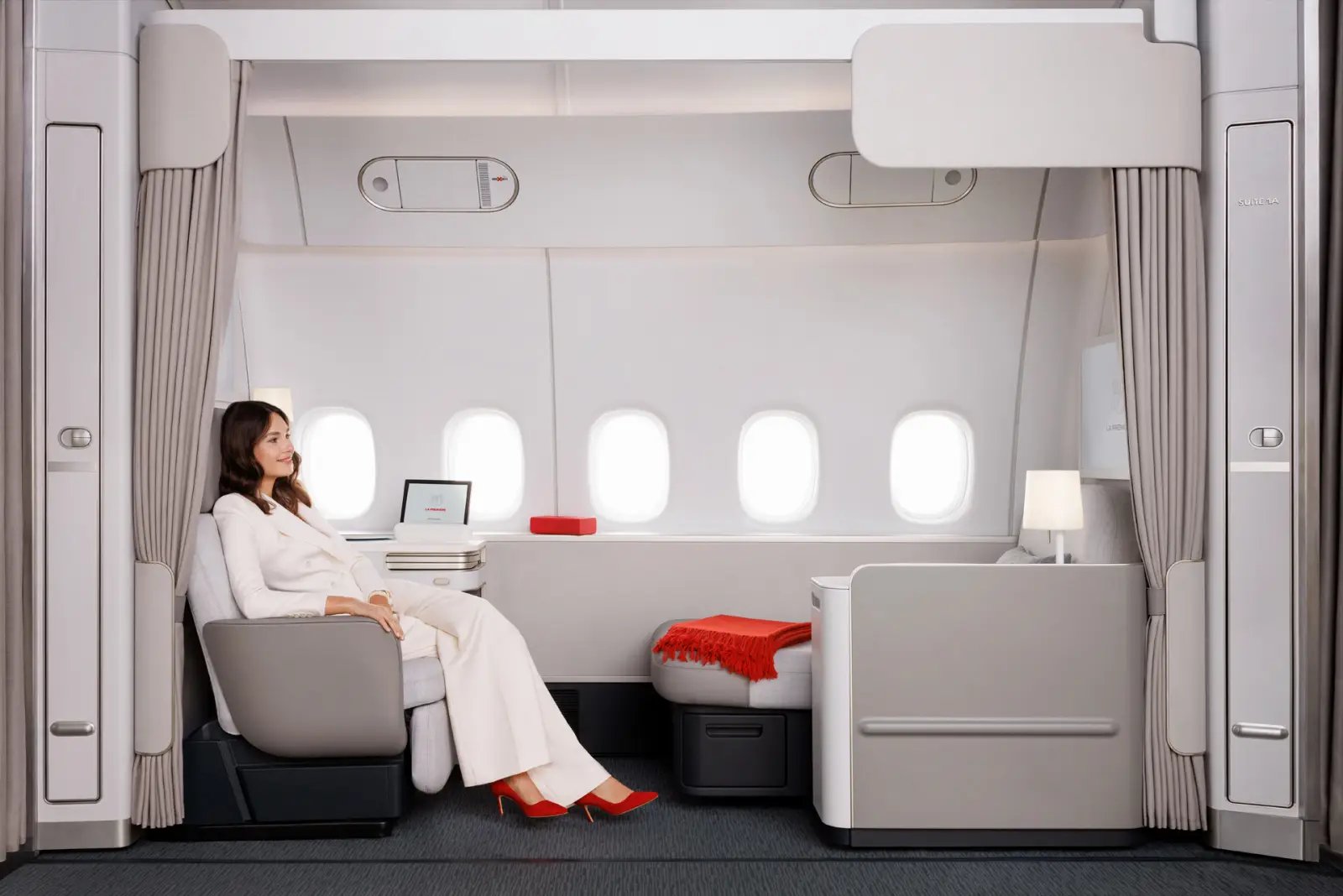 A woman seated comfortably in Air France’s new La Première suite with five windows, luxury seating, and privacy curtains in a Boeing 777-300ER.