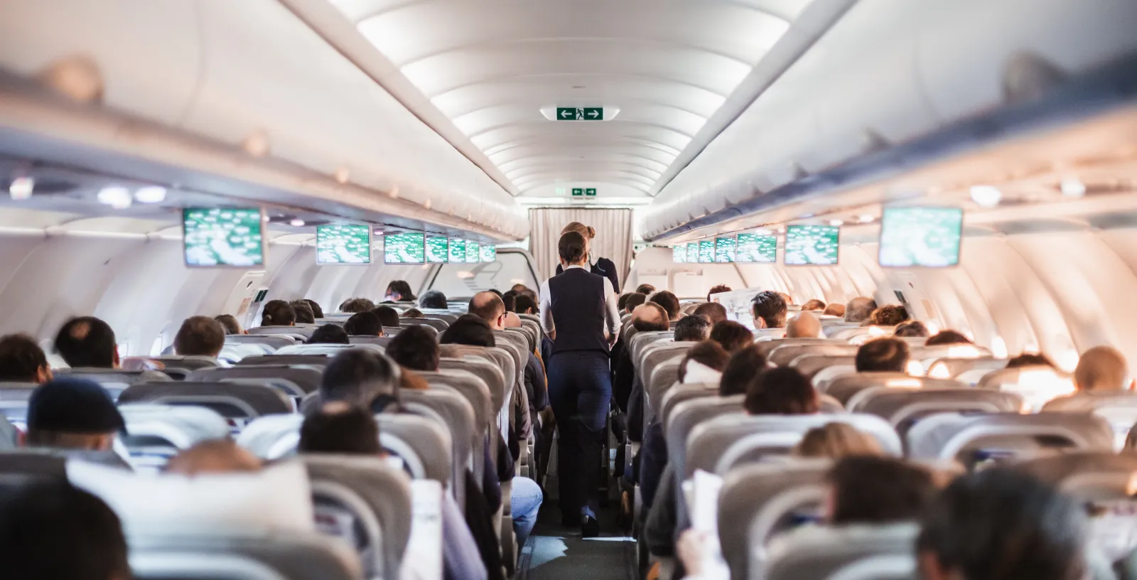 Why Airplane Cabins Are Pressurized — And What Happens If They’re Not 4 View of a crowded airplane cabin with passengers seated and flight attendants in the aisle.