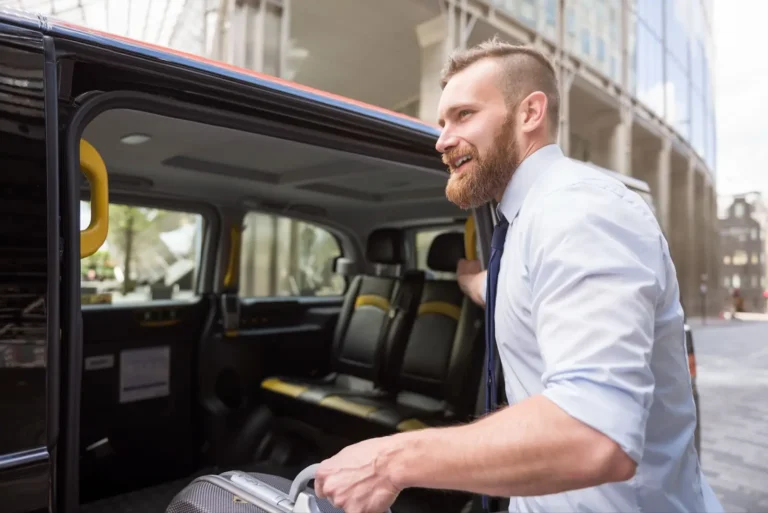 Technology 7 Business traveler smiling while loading luggage into a black taxi or shuttle van in an urban city setting.