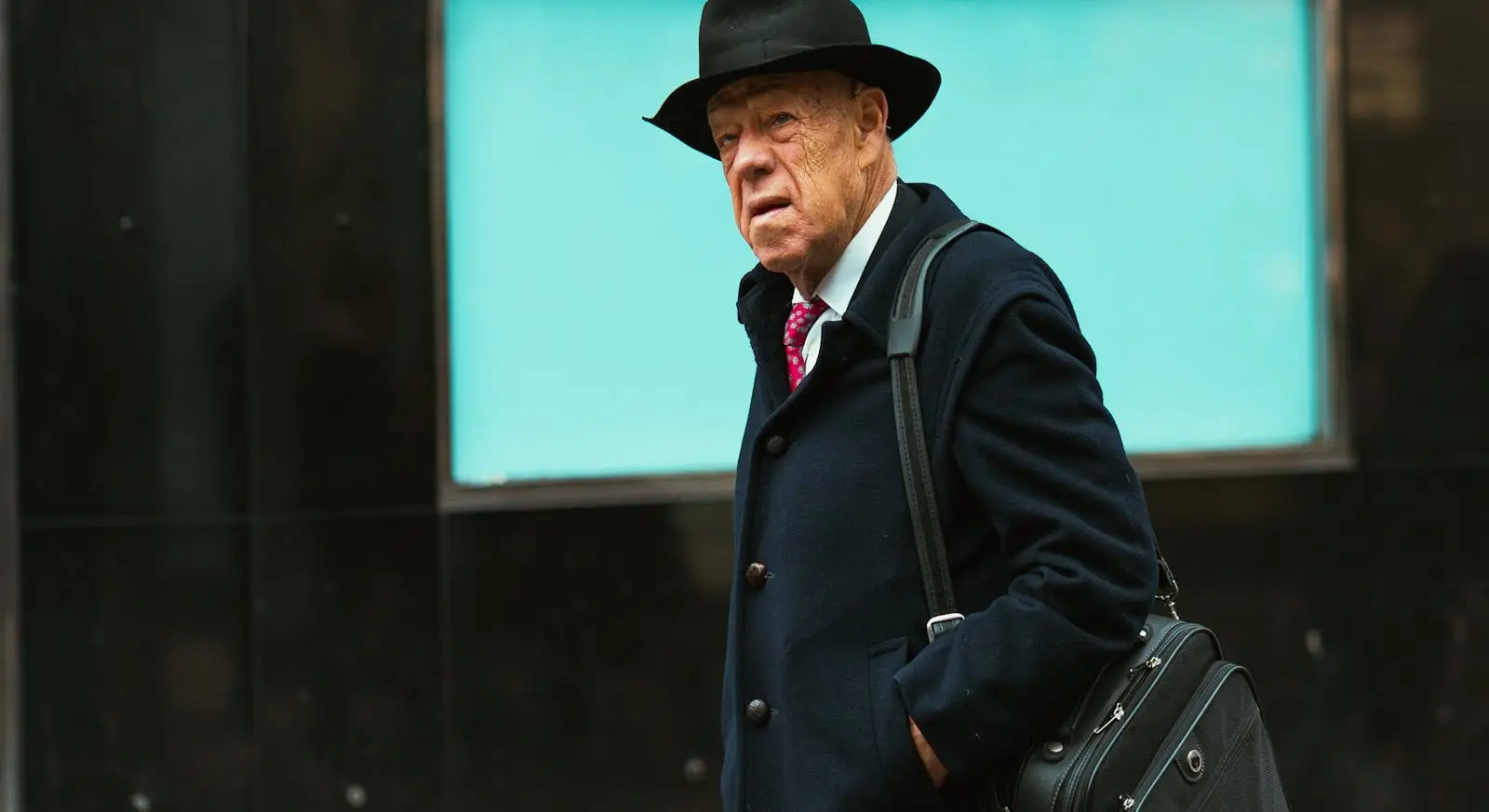 Age Is Just A Stamp: Travel Dreams Don’t Expire 3 Older man in coat and hat walking with a shoulder bag in an urban setting