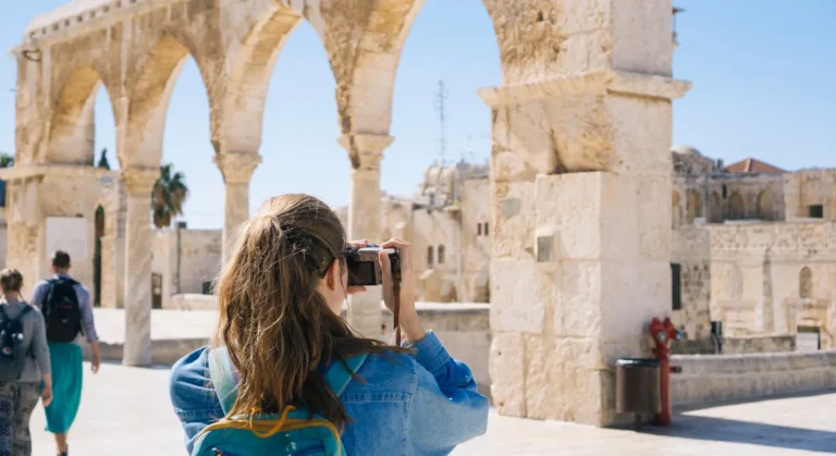 Technology 23 Tourist taking a photo of ancient stone arches at a historical site on a sunny day.