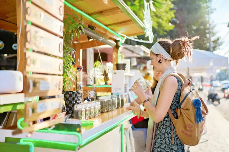 Tourist examining cannabis products at outdoor street stall in Thailand