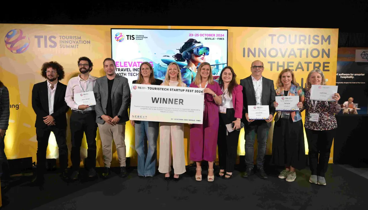 Group of Touristech Startup Fest 2024 winners holding certificates and a large winner check at the Tourism Innovation Summit in Seville.