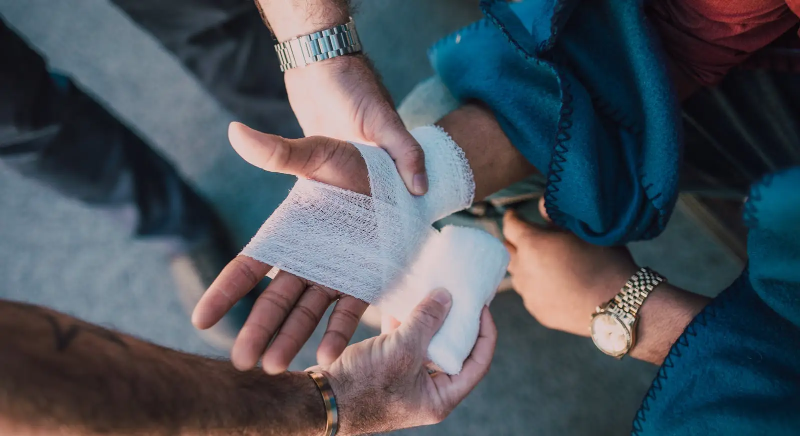 Close-up of a person's hand being wrapped in a white medical bandage after an injury