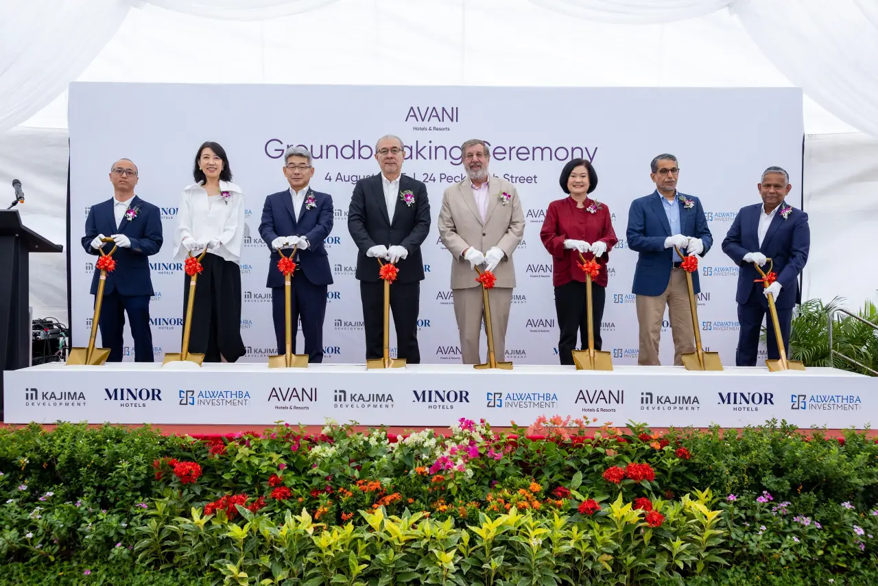 Executives and partners participate in the groundbreaking ceremony for the Avani Singapore hotel, holding gold shovels with red ribbons on stage.