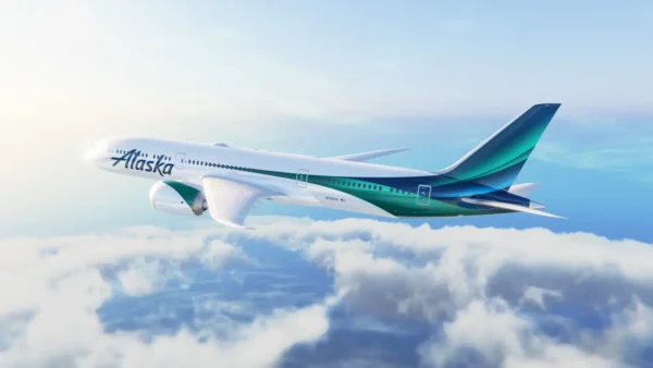 Home 11 Alaska Airlines Boeing 787 Dreamliner with new livery flying above the clouds on a clear day.