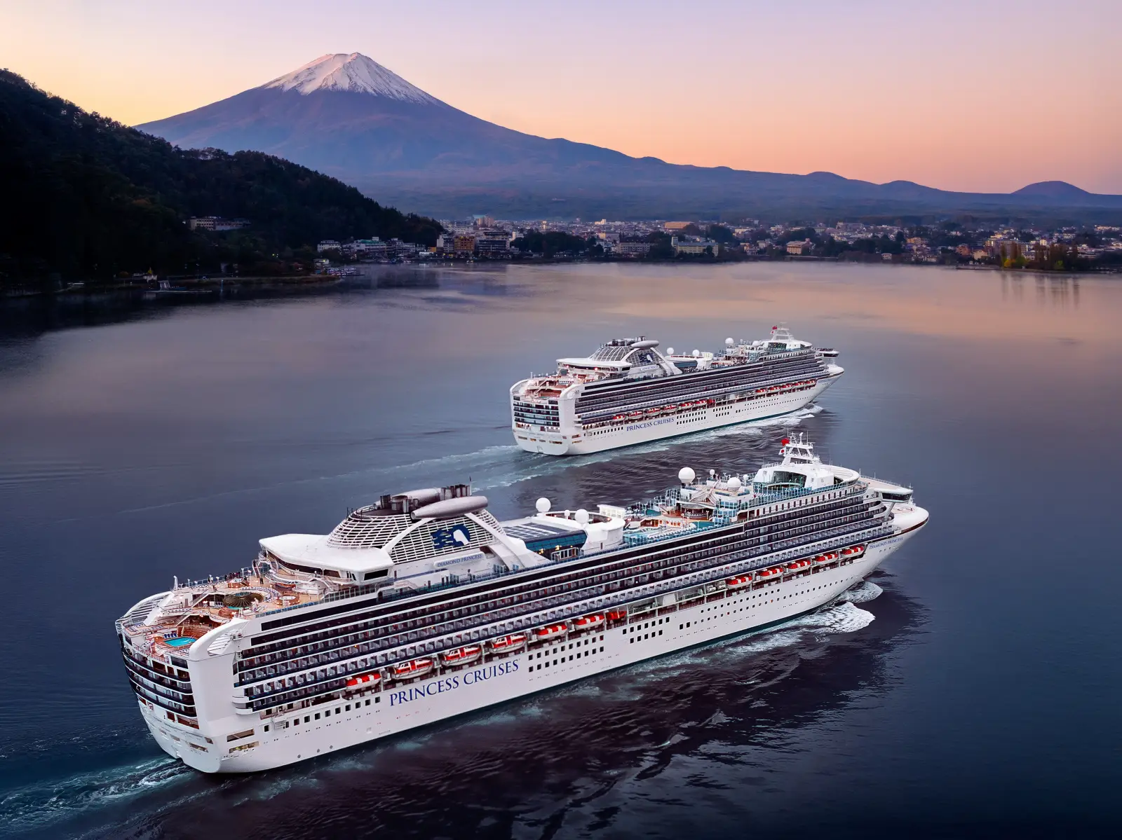 Princess Cruises' Sapphire Princess and Diamond Princess sailing in Japan with Mount Fuji in the background during a serene sunset.