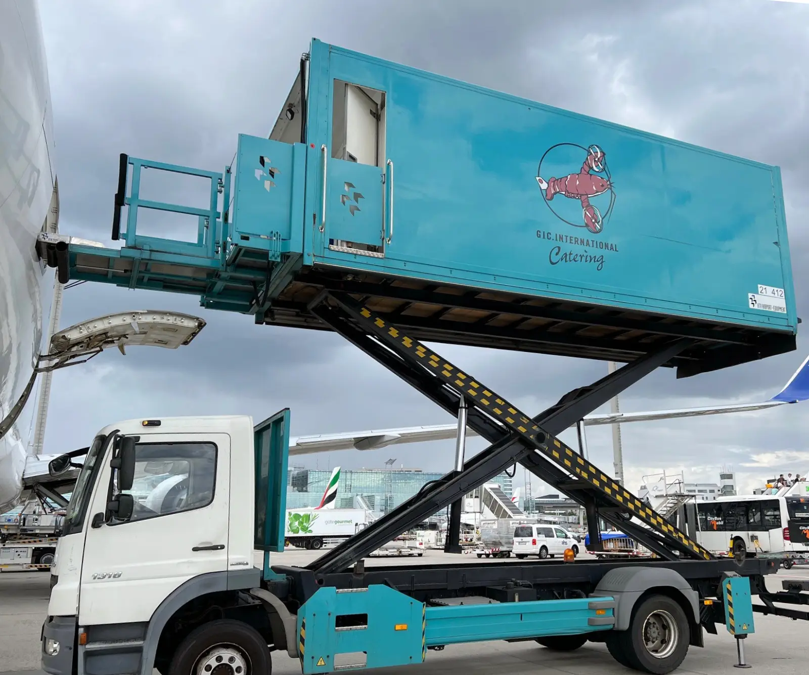 Aircraft catering truck from GIC International loading meals onto a plane at an airport.