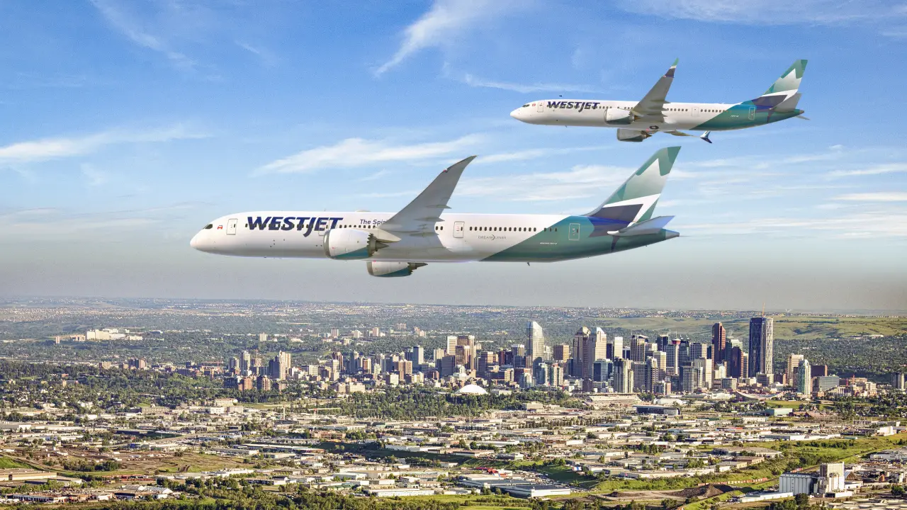 Two WestJet airplanes flying over Calgary skyline on a clear day.