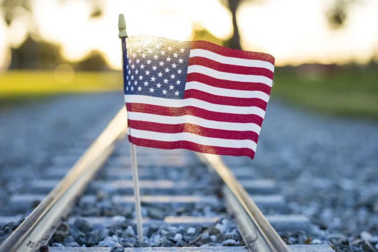 American flag on railroad track with sunlight in background