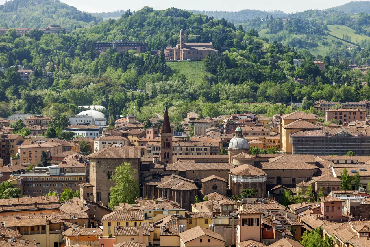 Vista aérea de Bolonia con terracota en la azotea, la torre de la iglesia y la colina verde en el fondo