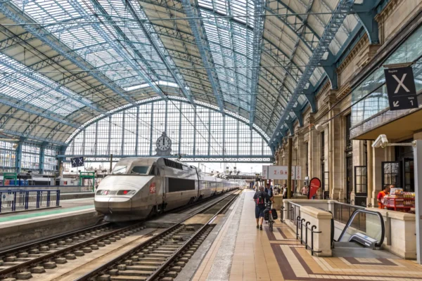 SNCF high-speed TGV train at Bordeaux Saint-Jean station under the glass roof, with passengers waiting on the platform.